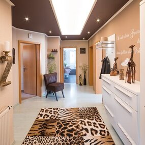 Moderner Flur mit afrikanischer Dekoration, Tiermusterteppich und stilvollen Möbeln.